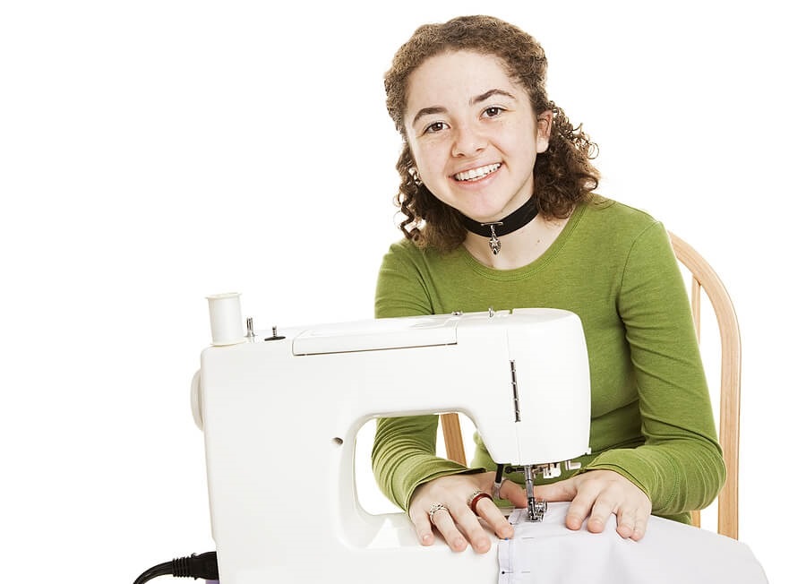 Teenager sitting at sewing maching