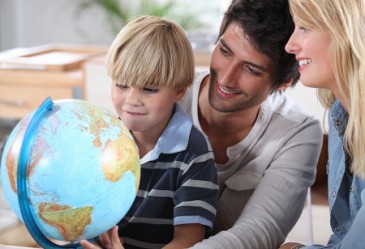 Parents in classroom with young child looking at globe